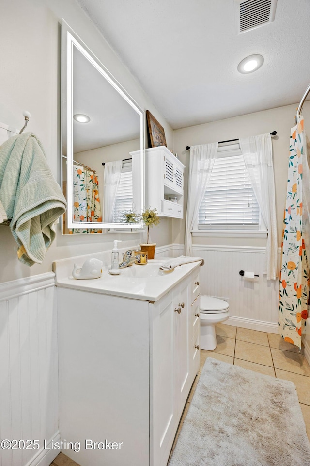 7513 Merlyn Cir, Louisville, KY 40214 - bathroom featuring vanity, toilet, plenty of natural light, a wainscoted wall, and tile patterned floors