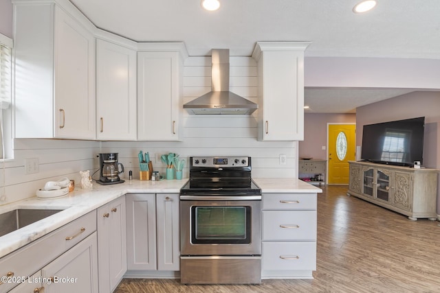 5704 Bartview Ct, Louisville, KY 40229 - kitchen with wall chimney range hood, stainless steel electric range, light wood finished floors, white cabinets, and recessed lighting