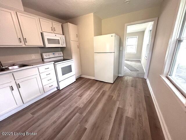638 Gheens Ave, Louisville, KY 40214 - kitchen featuring white appliances, white cabinets, baseboards, dark wood-type flooring, and a textured ceiling