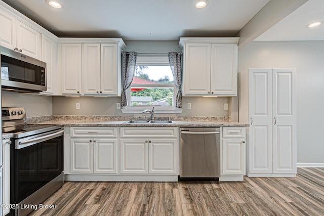 1507 Glenrock Rd, Louisville, KY 40216 - kitchen with appliances with stainless steel finishes, a sink, light wood-style flooring, white cabinets, and recessed lighting