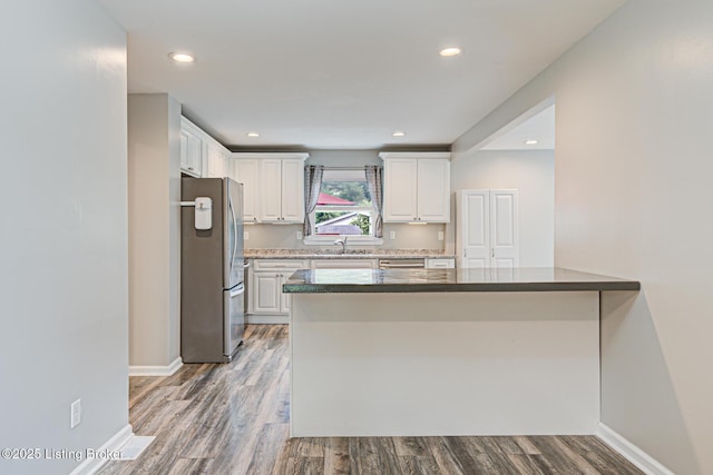 1507 Glenrock Rd, Louisville, KY 40216 - kitchen with appliances with stainless steel finishes, a sink, a peninsula, white cabinetry, and wood finished floors