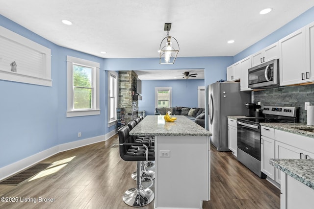 3106 Ramser Ave, Louisville, KY 40216 - kitchen with appliances with stainless steel finishes, a center island, a kitchen breakfast bar, backsplash, and white cabinetry