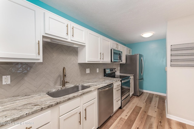 10304 Southern Meadows Dr Unit 101, Louisville, KY 40241 - kitchen featuring stainless steel appliances, a sink, backsplash, white cabinetry, and light wood finished floors