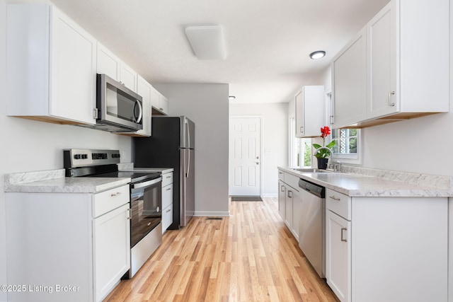 10518 Fairview Ave, Louisville, KY 40299 - kitchen with appliances with stainless steel finishes, light wood-type flooring, white cabinetry, a sink, and light countertops