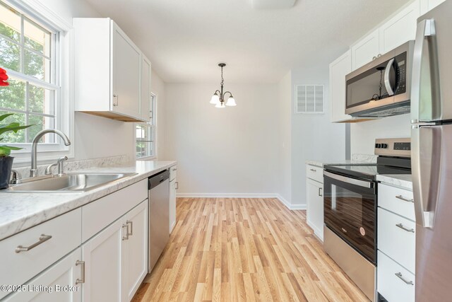 10518 Fairview Ave, Louisville, KY 40299 - kitchen with appliances with stainless steel finishes, a sink, a chandelier, light wood finished floors, and white cabinetry