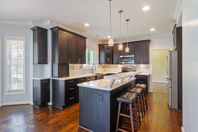 3613 Wynbrooke Cir, Louisville, KY 40241 - kitchen featuring appliances with stainless steel finishes, a center island, backsplash, dark wood-type flooring, and light countertops