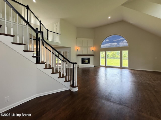 5101 Elm Tree Pl, Louisville, KY 40299 - unfurnished living room featuring baseboards, wood finished floors, a glass covered fireplace, high vaulted ceiling, and stairs