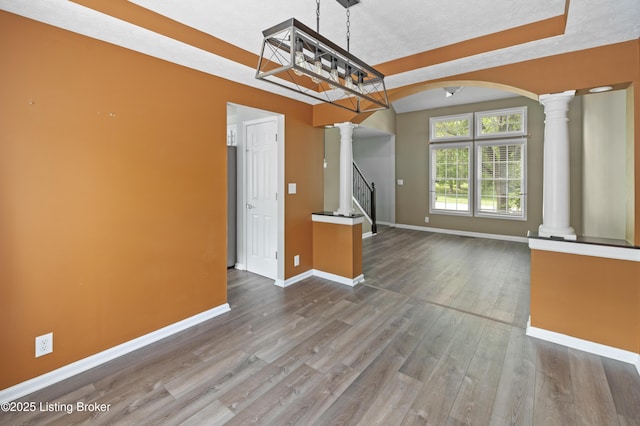 12308 Dominion Way, Louisville, KY 40299 - unfurnished dining area with ornate columns, baseboards, arched walkways, wood finished floors, and stairway