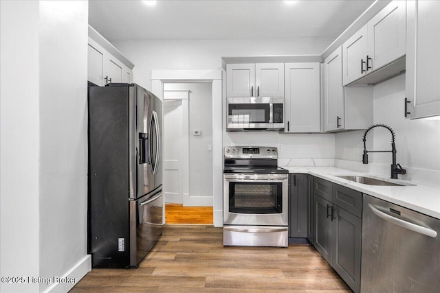 1907 Culbertson Ave, New Albany, IN 47150 - kitchen featuring stainless steel appliances, a sink, gray cabinets, light wood finished floors, and baseboards