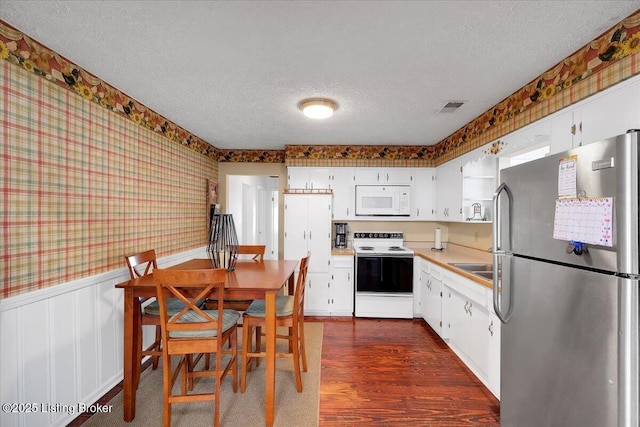 8400 Wisertown Rd, Louisville, KY 40214 - kitchen featuring freestanding refrigerator, electric range, white microwave, wallpapered walls, and a textured ceiling