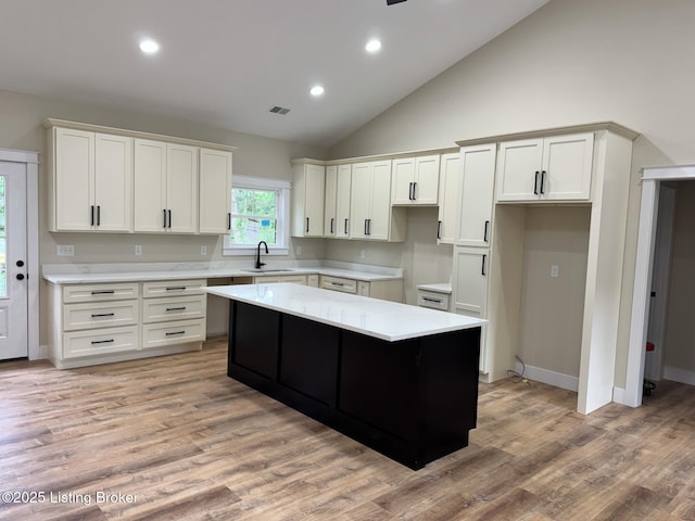 57 Malvern Ct, Brandenburg, KY 40108 - kitchen with a kitchen island, white cabinetry, light wood-style flooring, light countertops, and high vaulted ceiling