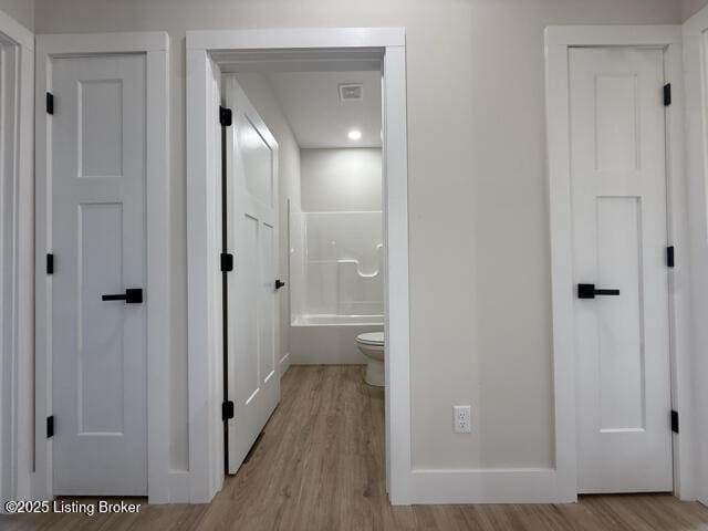 49 Roy Rd, Eastview, KY 42732 - bathroom featuring wood finished floors, toilet, baseboards, and washtub / shower combination