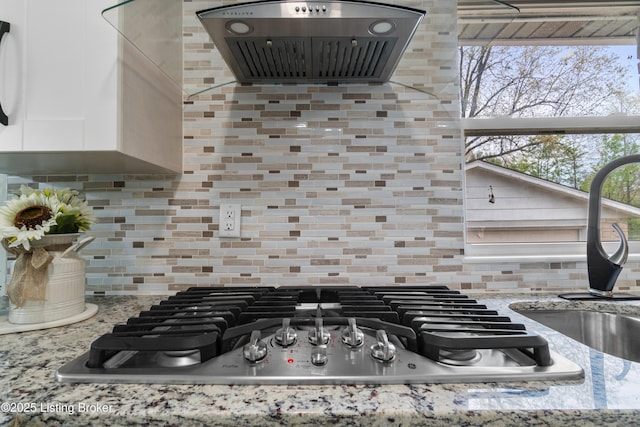 4328 Dohn Ave, Louisville, KY 40216 - kitchen view of stainless steel gas stovetop, extractor fan, white cabinets, and tasteful backsplash
