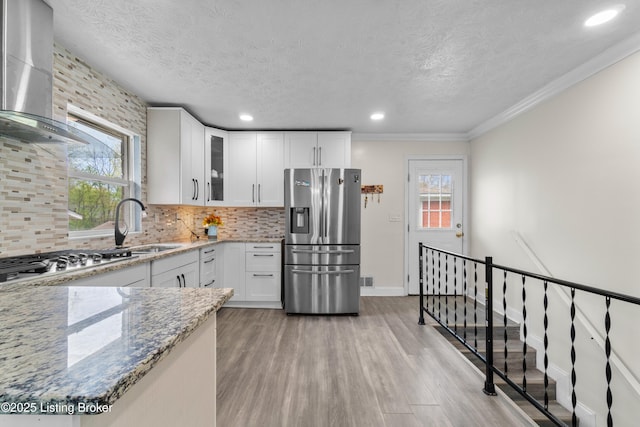 4328 Dohn Ave, Louisville, KY 40216 - kitchen featuring stainless steel appliances, wall chimney range hood, light stone counters, light wood-style flooring, and a textured ceiling