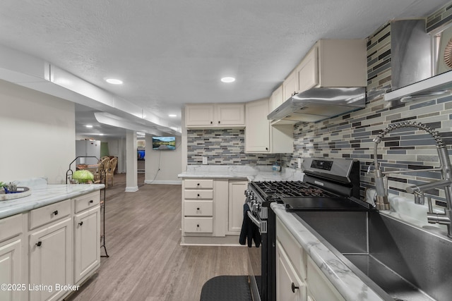4328 Dohn Ave, Louisville, KY 40216 - kitchen with stainless steel range with gas stovetop, range hood, a sink, light wood-style floors, and decorative backsplash
