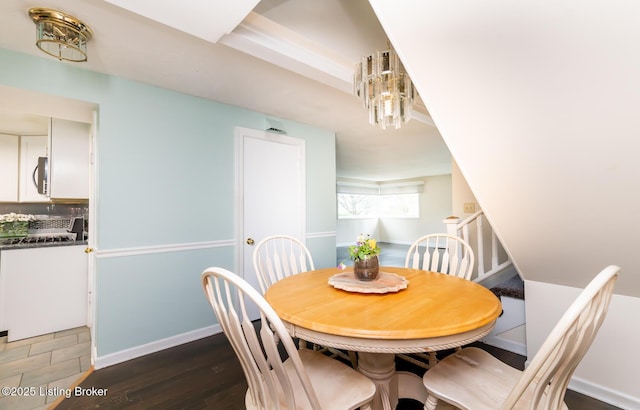 1031 Thruston Ave, Louisville, KY 40217 - dining room featuring dark wood finished floors, stairs, baseboards, and a chandelier