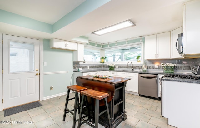 1031 Thruston Ave, Louisville, KY 40217 - kitchen with stainless steel appliances, a sink, dark countertops, decorative backsplash, and white cabinets