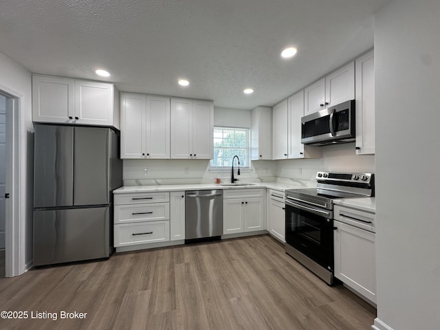 1129 Willow Oak Ln, La Grange, KY 40031 - kitchen featuring appliances with stainless steel finishes, a sink, wood finished floors, white cabinetry, and light countertops