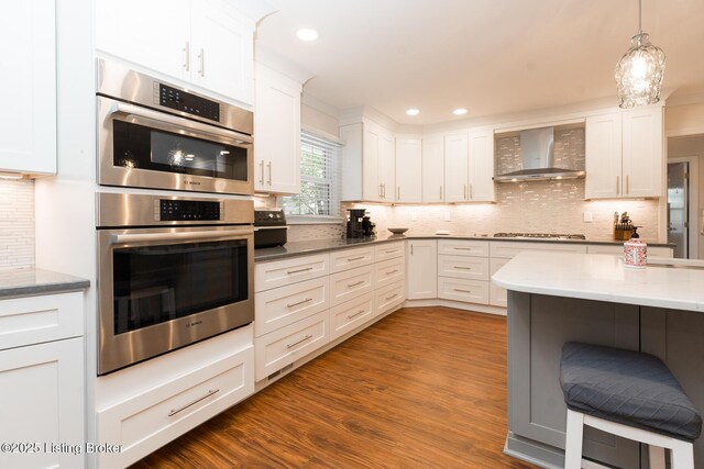 2401 Branning Rd, Thornhill, KY 40222 - kitchen with wall chimney range hood, double oven, backsplash, white cabinets, and dark wood-type flooring