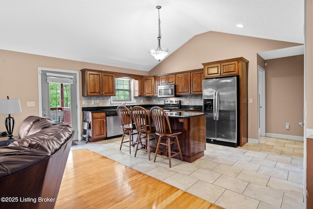 90 Chancellor Ct, Elizabethtown, KY 42701 - kitchen featuring stainless steel appliances, dark countertops, open floor plan, a kitchen bar, and brown cabinetry