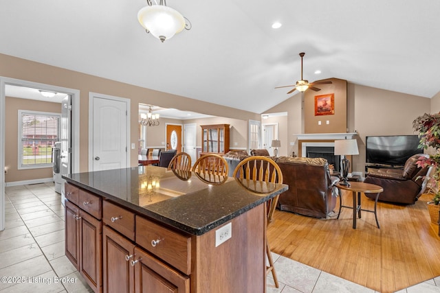 90 Chancellor Ct, Elizabethtown, KY 42701 - kitchen featuring a kitchen breakfast bar, a fireplace, brown cabinets, light tile patterned floors, and vaulted ceiling