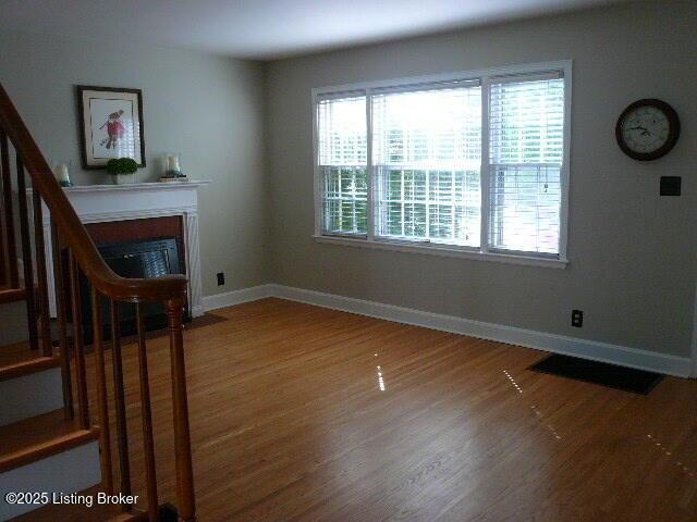 1411 Falcon Dr, Louisville, KY 40213 - unfurnished living room with wood finished floors, stairs, baseboards, and a fireplace with flush hearth