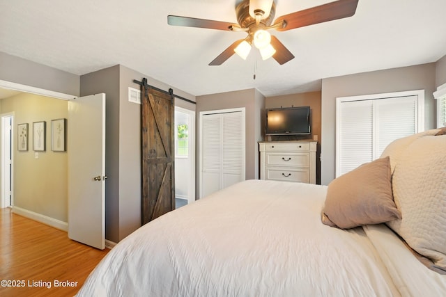 828 Dorsey Ln, Louisville, KY 40223 - bedroom featuring two closets, light wood-style floors, baseboards, a barn door, and ceiling fan