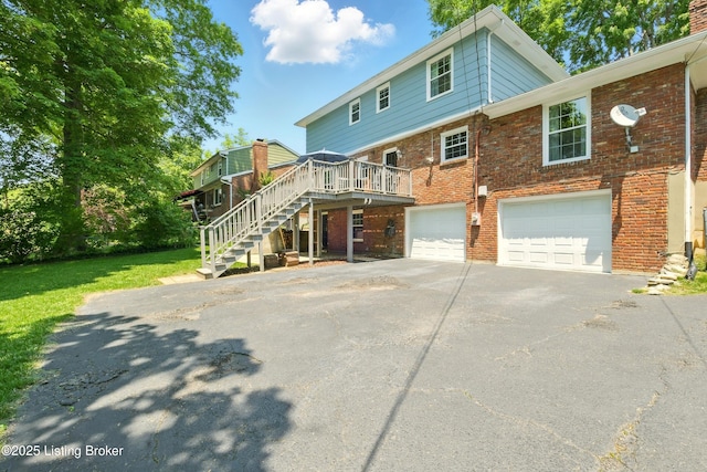 828 Dorsey Ln, Louisville, KY 40223 - back of house with asphalt driveway, stairs, a garage, brick siding, and a lawn