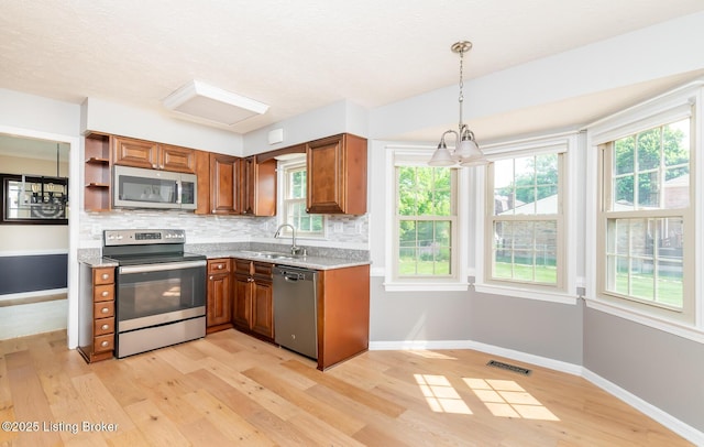 1311 Pollitt Ct, Louisville, KY 40223 - kitchen featuring appliances with stainless steel finishes, light wood-style flooring, brown cabinets, backsplash, and a sink