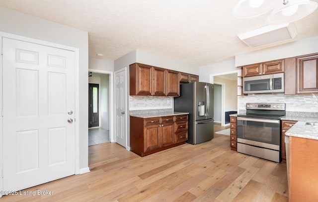 1311 Pollitt Ct, Louisville, KY 40223 - kitchen with appliances with stainless steel finishes, light wood-style floors, backsplash, and brown cabinetry