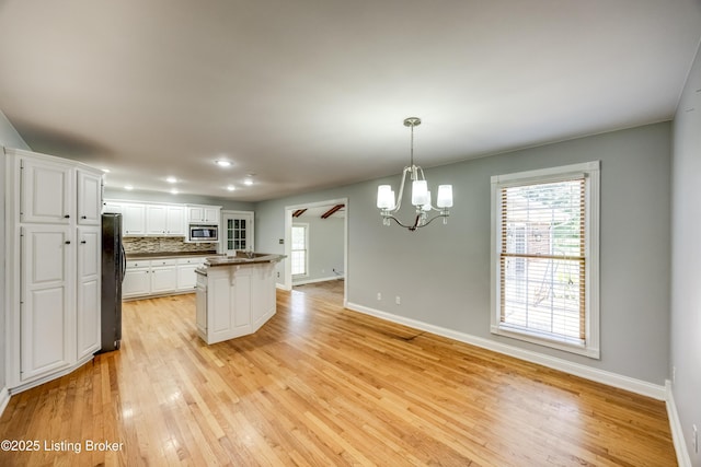 1124 Foxfire Rd, Bardstown, KY 40004 - kitchen with freestanding refrigerator, stainless steel microwave, a chandelier, white cabinetry, and light wood-style flooring