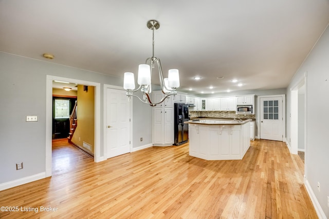 1124 Foxfire Rd, Bardstown, KY 40004 - kitchen featuring stainless steel microwave, a chandelier, light wood-type flooring, black fridge, and white cabinetry