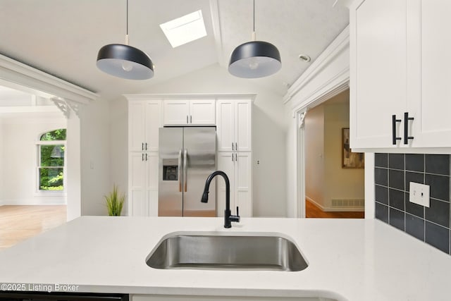 5115 Stony Brook Dr, Louisville, KY 40291 - kitchen with stainless steel fridge, a sink, lofted ceiling, white cabinets, and wood finished floors