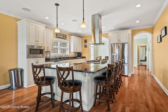 15323 Royal Troon Ave, Louisville, KY 40245 - kitchen featuring appliances with stainless steel finishes, island range hood, arched walkways, a kitchen breakfast bar, and tasteful backsplash
