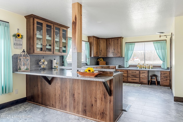 3412 Boyds Knob Rd, Munfordville, KY 42765 - kitchen with decorative backsplash, a peninsula, brown cabinets, healthy amount of natural light, and a textured ceiling