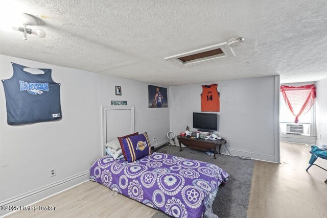 2733 Dumesnil St, Louisville, KY 40211 - bedroom featuring attic access, a textured ceiling, wood finished floors, and a wall mounted air conditioner