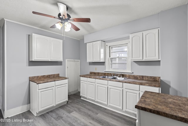 2733 Dumesnil St, Louisville, KY 40211 - kitchen featuring dark countertops, white cabinets, ceiling fan, wood finished floors, and a textured ceiling