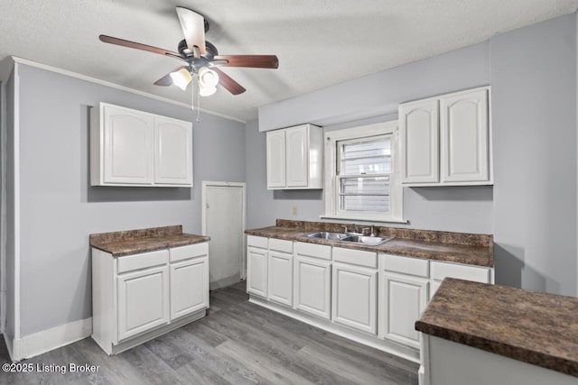 2733 Dumesnil St, Louisville, KY 40211 - kitchen featuring dark countertops, white cabinets, wood finished floors, a ceiling fan, and a textured ceiling