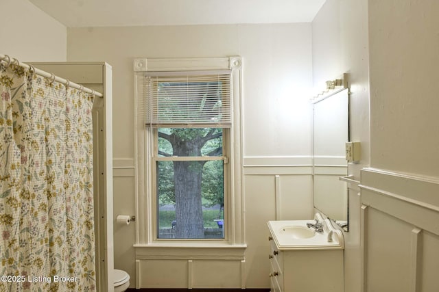513 Camp St, Louisville, KY 40203 - full bath with a decorative wall, vanity, toilet, a shower with shower curtain, and a wainscoted wall