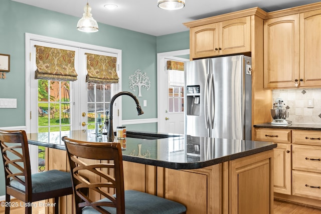 6400 Cedar Branch Ct, Louisville, KY 40291 - kitchen with stainless steel fridge, a breakfast bar area, decorative backsplash, a center island with sink, and dark stone counters