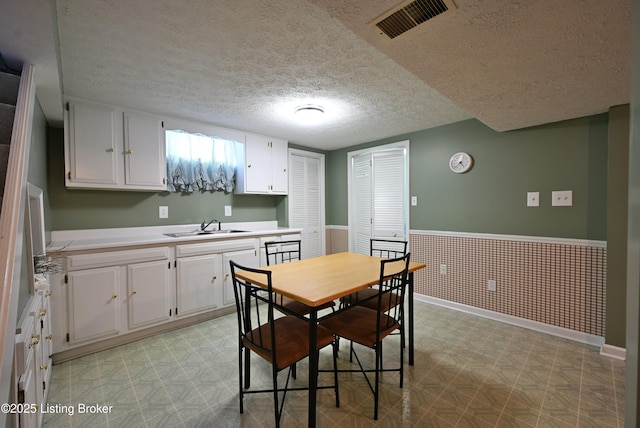 4913 D Lue Ct, Louisville, KY 40216 - dining area with light floors, a textured ceiling, wainscoting, and baseboards
