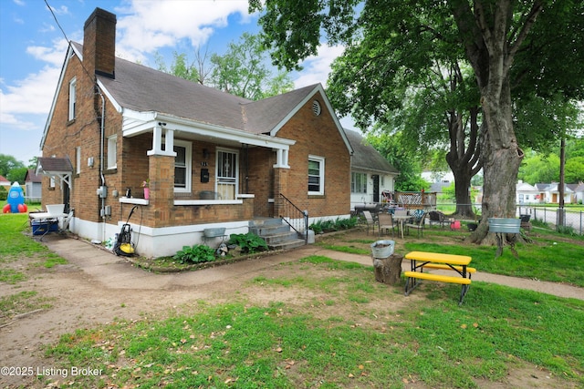 315 N 27th St, Louisville, KY 40212 - view of front facade with a chimney, brick siding, covered porch, and roof with shingles