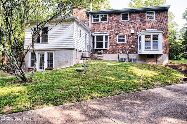 3325 Chenoweth Run Rd, Louisville, KY 40299 - rear view of property with a yard, brick siding, a chimney, and central AC unit