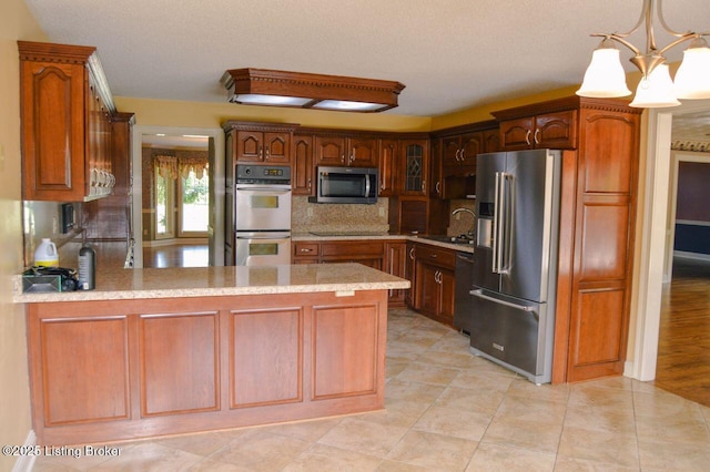 166 Castleton Dr, Bardstown, KY 40004 - kitchen with appliances with stainless steel finishes, a peninsula, backsplash, a chandelier, and pendant lighting