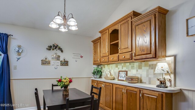 1625 Tina Ct, La Grange, KY 40031 - kitchen featuring a chandelier, brown cabinets, decorative backsplash, light countertops, and wainscoting