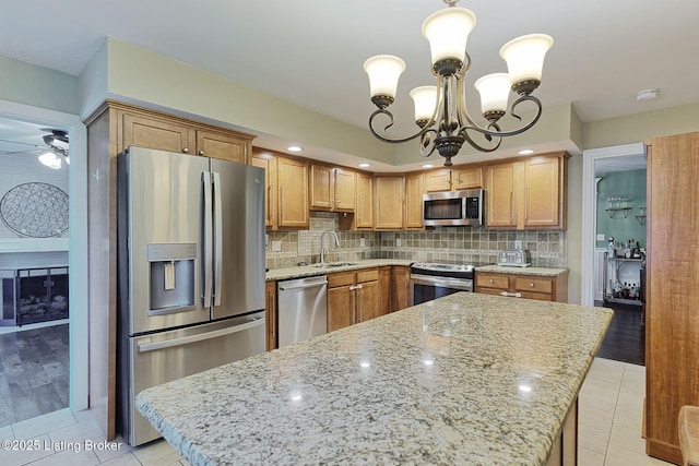 1007 Girard Dr, Louisville, KY 40222 - kitchen featuring appliances with stainless steel finishes, a chandelier, decorative backsplash, light stone counters, and a sink