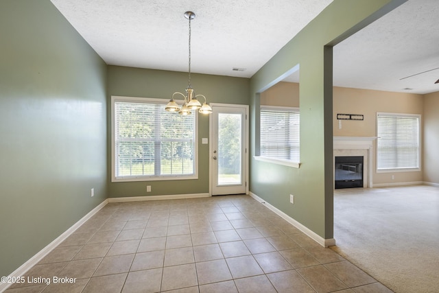 8811 Eli Dr, Louisville, KY 40291 - unfurnished dining area featuring a textured ceiling, healthy amount of natural light, a chandelier, a glass covered fireplace, and tile patterned flooring