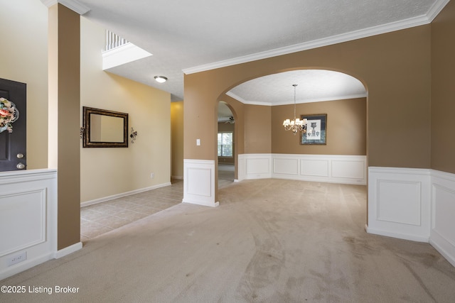 8811 Eli Dr, Louisville, KY 40291 - empty room featuring arched walkways, light carpet, a chandelier, wainscoting, and crown molding
