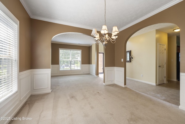 8811 Eli Dr, Louisville, KY 40291 - empty room featuring arched walkways, light carpet, a chandelier, ornamental molding, and a wainscoted wall