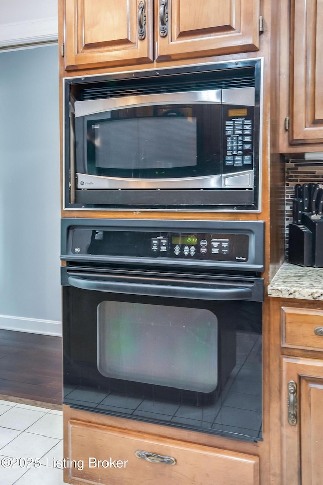 2508 Windsor Forest Dr, Louisville, KY 40272 - kitchen view of stainless steel microwave, oven, baseboards, brown cabinetry, and light stone countertops